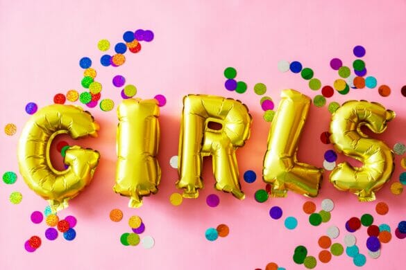 Mylar gold balloons spelling out 'girls' and surrounded by large confetti