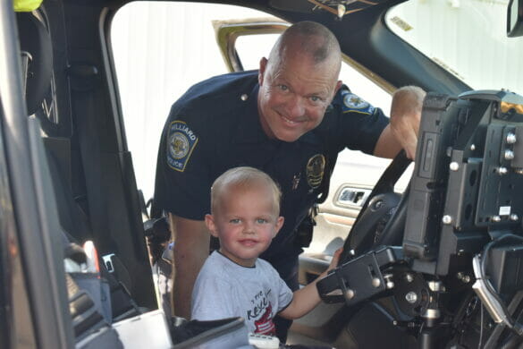 Officer posing with little boy in a cruiser