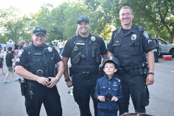 Little boy dressed as an officer posing with 3 officers