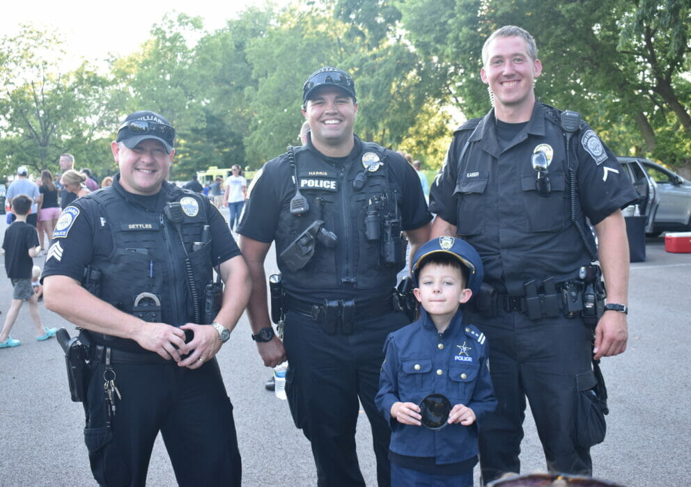 Little boy dressed as an officer posing with 3 officers
