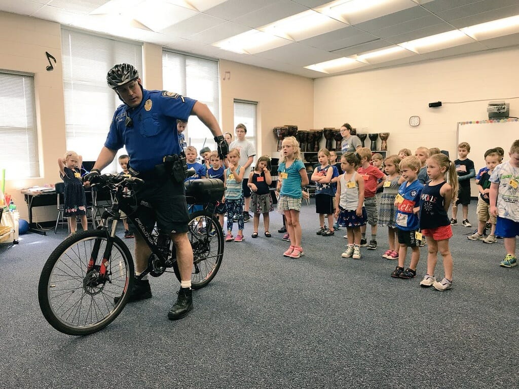 Officer demonstrating bike safety to kids