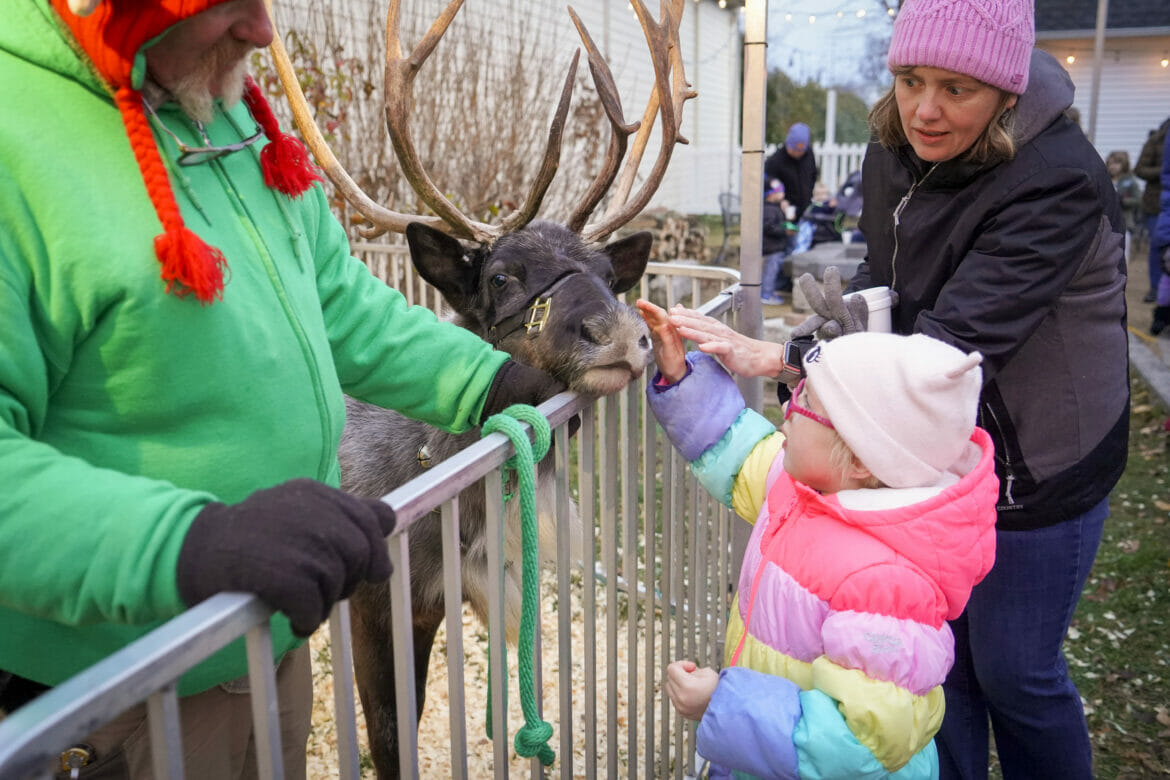 A little girl and her mom petting a reindeer