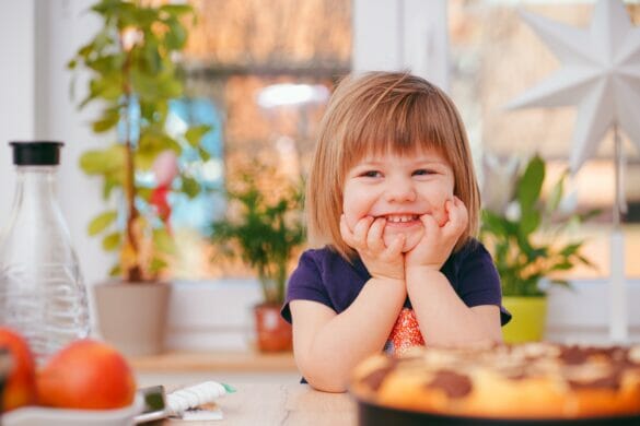 Little girl sitting at table with food in front of her