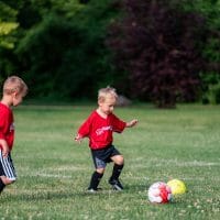 Two little boys kicking a soccer ball