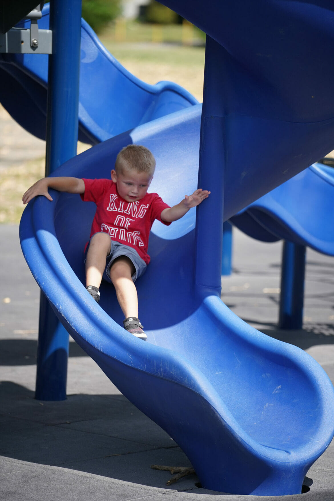 A boy sliding down a blue slide