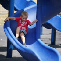 A boy sliding down a blue slide