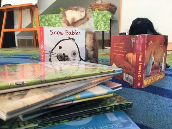 Little girl reading beside a stack of books