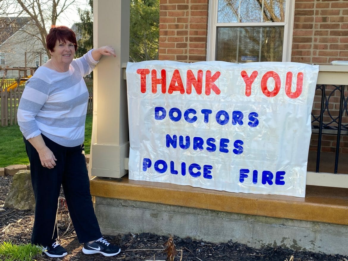 Woman standing next to sign thanking first responders