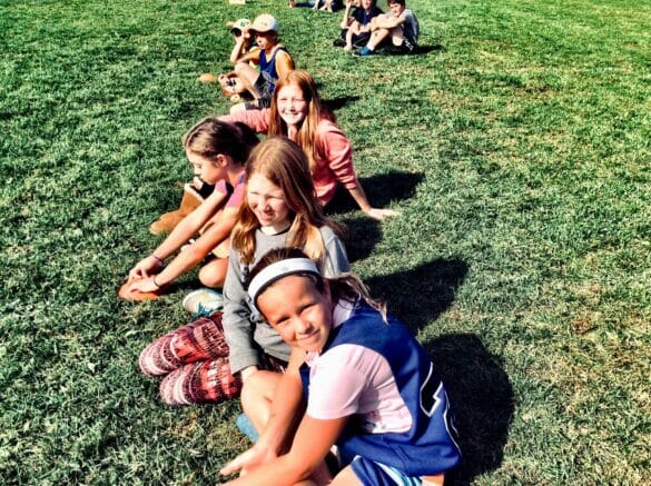 A group of girls lined up, sitting on grass