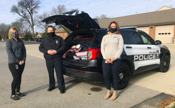 Kristan, Angela, and an officer standing beside a cruiser filled with donated clothes