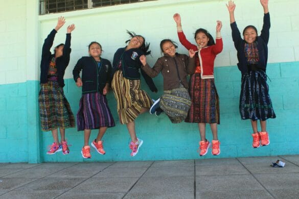 A group of girls jumping n the air, wearing colorful shoes