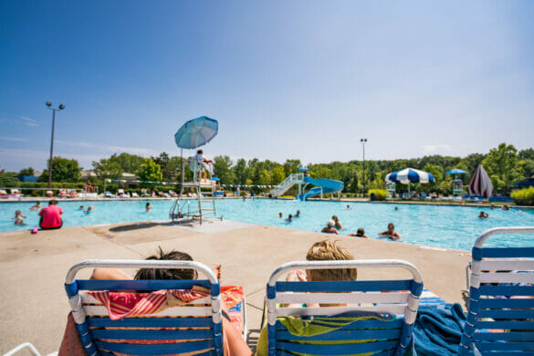 Two women reclining on beach chairs, looking out at people in the pool