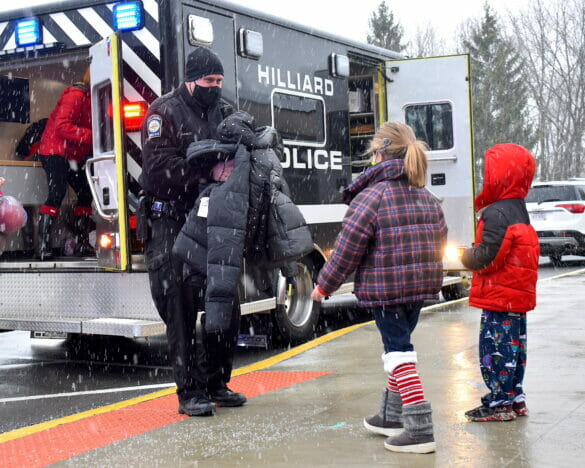 Officers giving kids coats in the snow