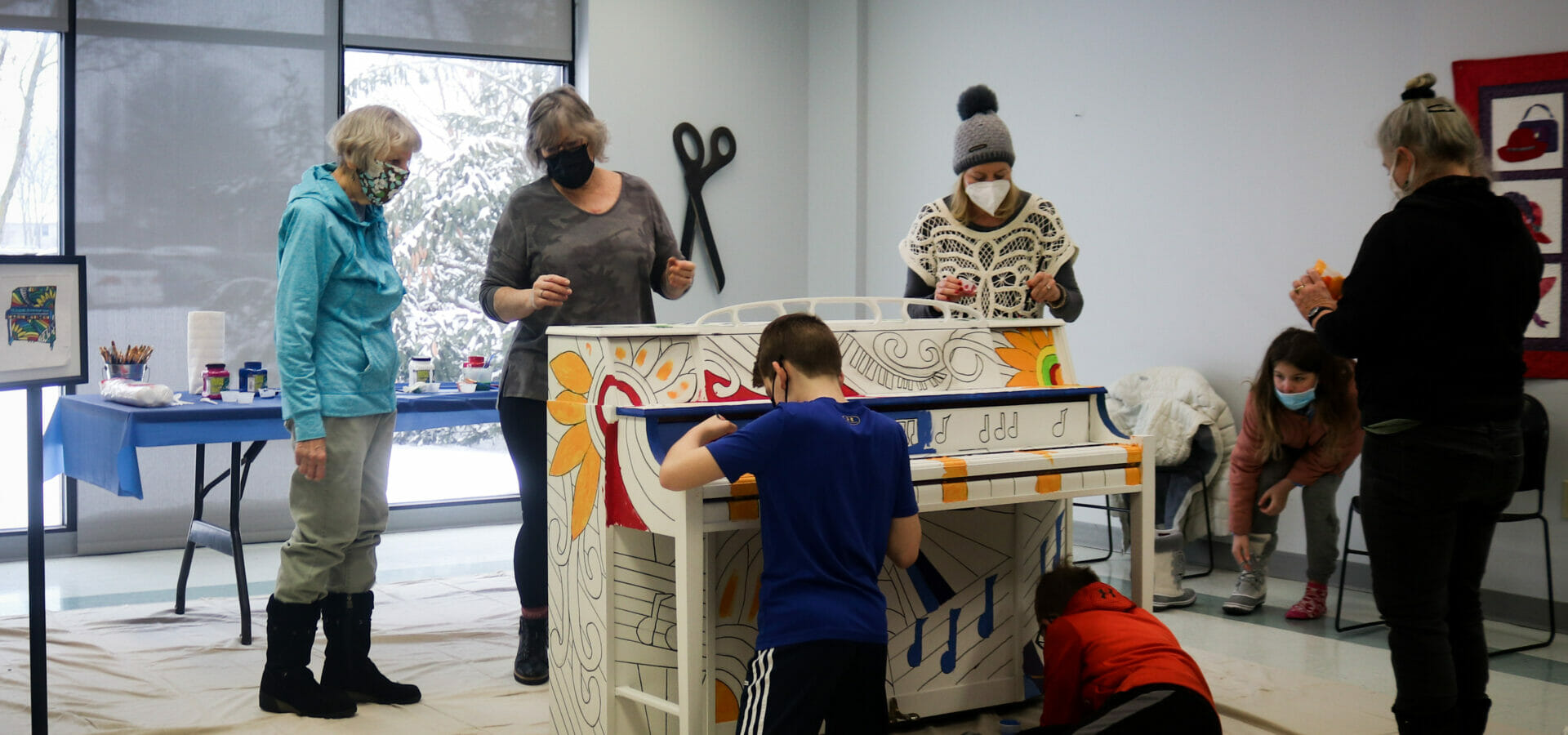 volunteers painting a piano.