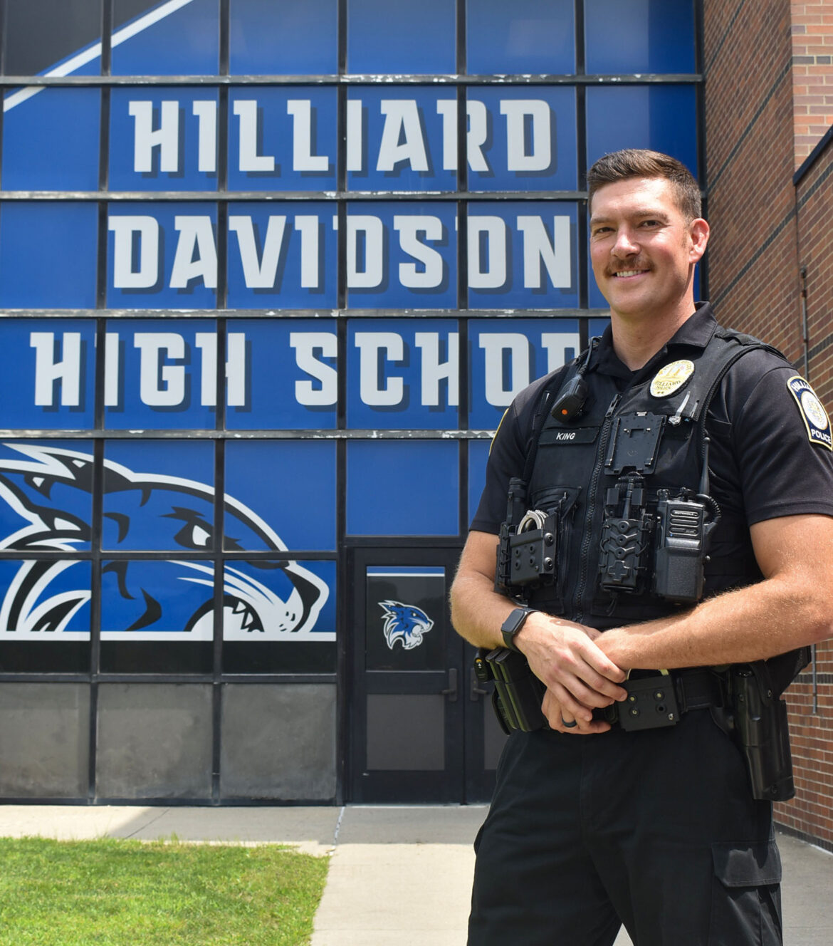 Officer stands in front of Hilliard Davidson High School. 