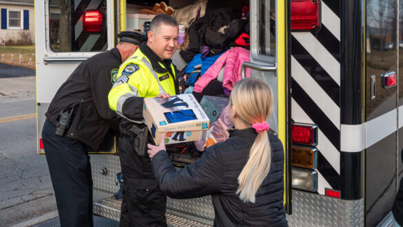 A Hilliard police officers hands a pair of snow boots to a child as part of the Cram the Cruiser drive.