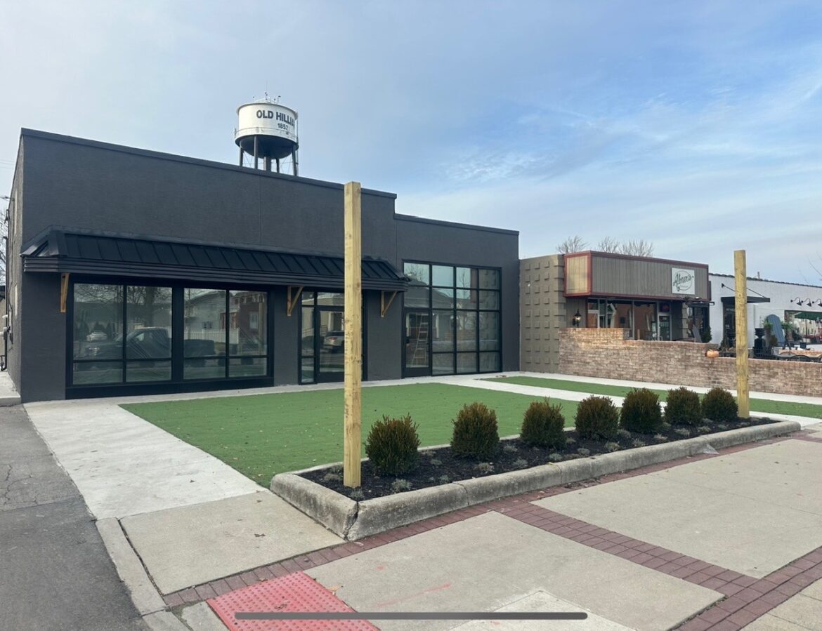 A building on Main Street in downtown Hilliard, Ohio, undergoing renovation with fresh gray paint and new AstroTurf on the front lawn.