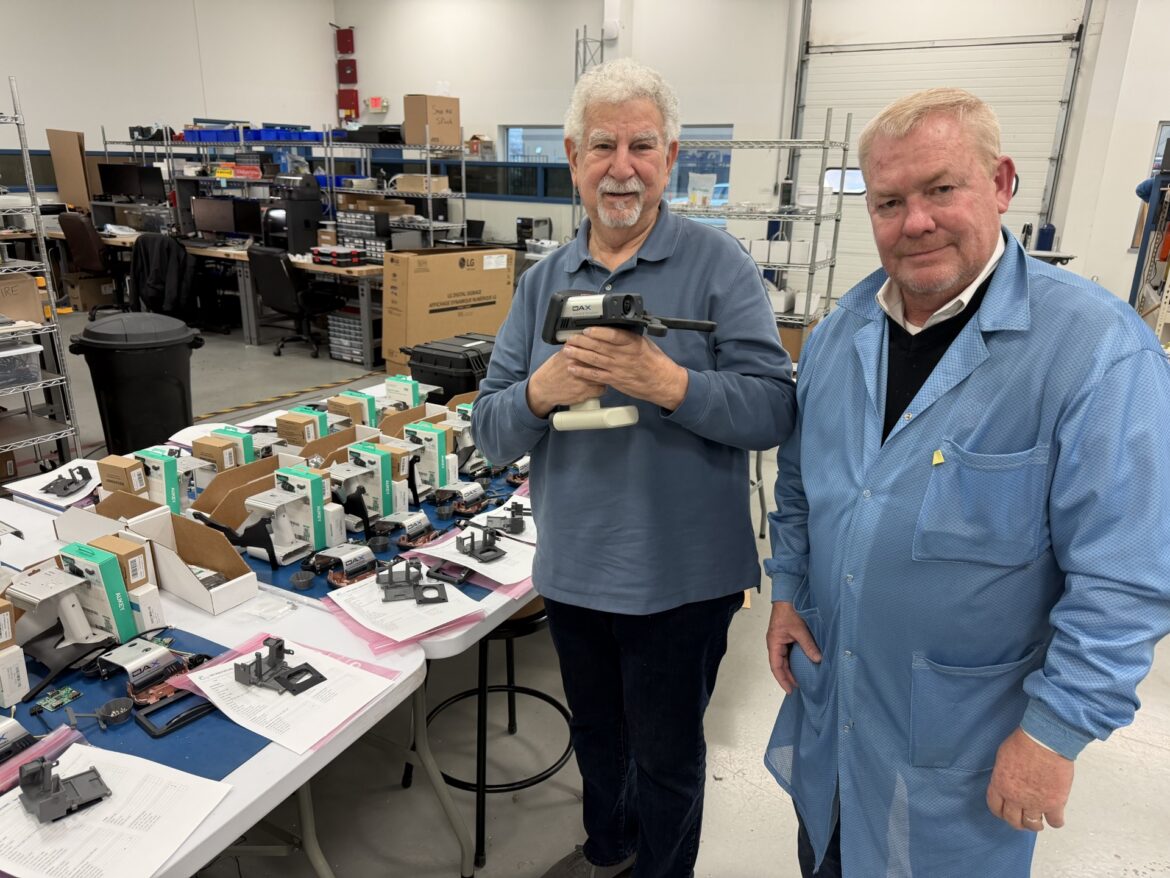 Ron Waldorf and John Bair pose for a photo holding the DAX Evidence Recorder at the Converge Technologies lab.