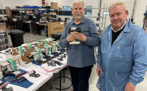 Ron Waldorf and John Bair pose for a photo holding the DAX Evidence Recorder at the Converge Technologies lab.