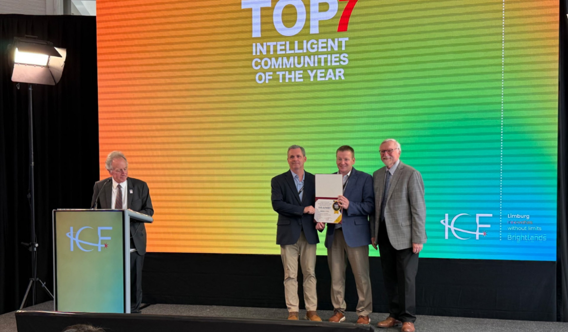 Duane Powell and David Meadows accept the Top7 Intelligent Community Award on stage at the 2026 Top7 Conference in Brightlands-Limburg, Netherlands.